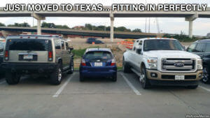 big trucks in Texas with smaller car parked between them 