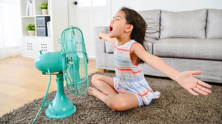 keep cool in summer with the right thermostat settting; girl in front of a fan
