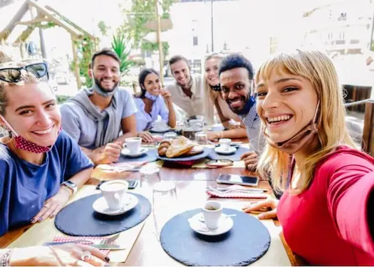 group of people at a dining table in a restaurant looking at camera selfie