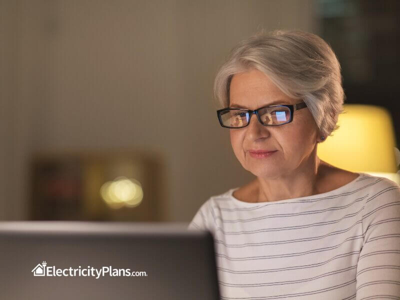 A senior citizen using a laptop or tablet, reviewing bills or electricity plans.
