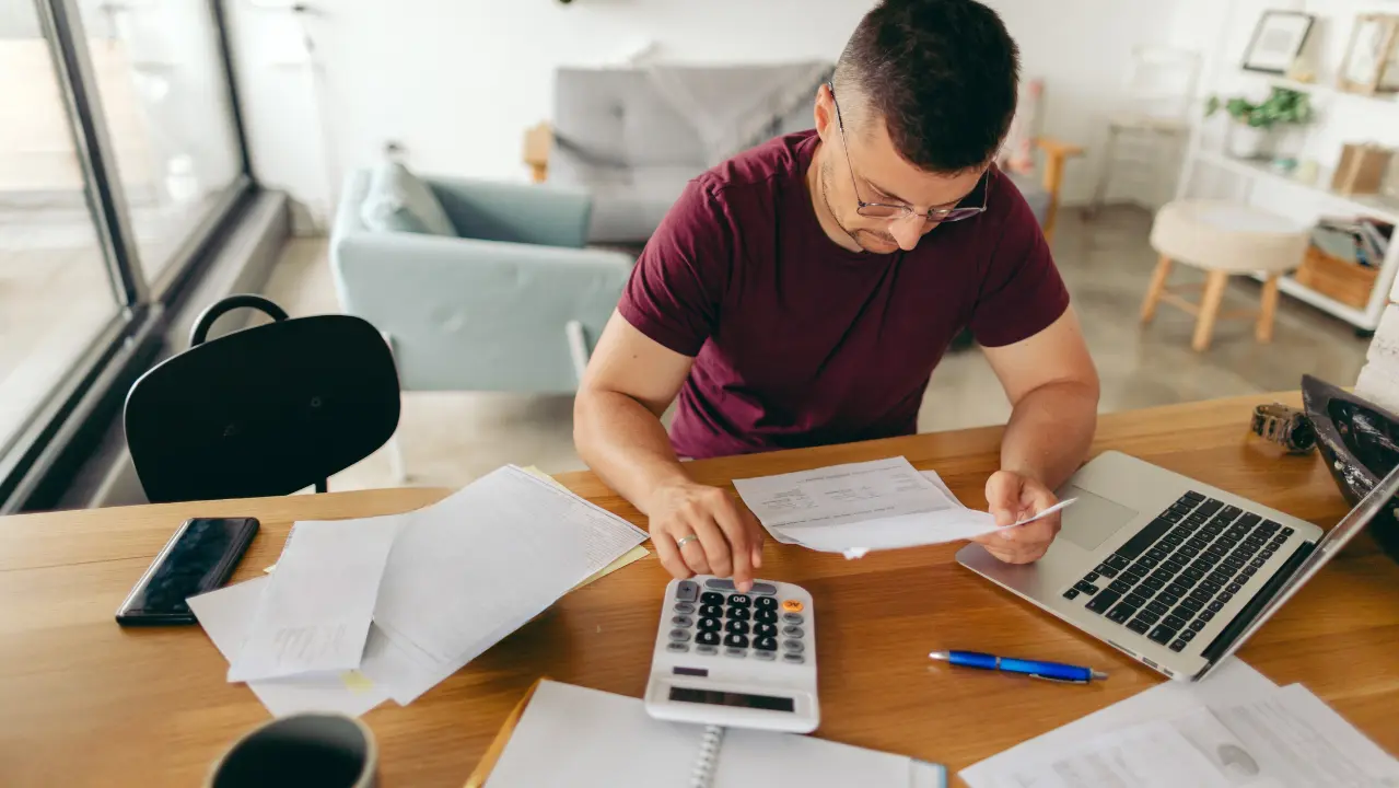 man reviews his electricity bill using a calculator to find savings.